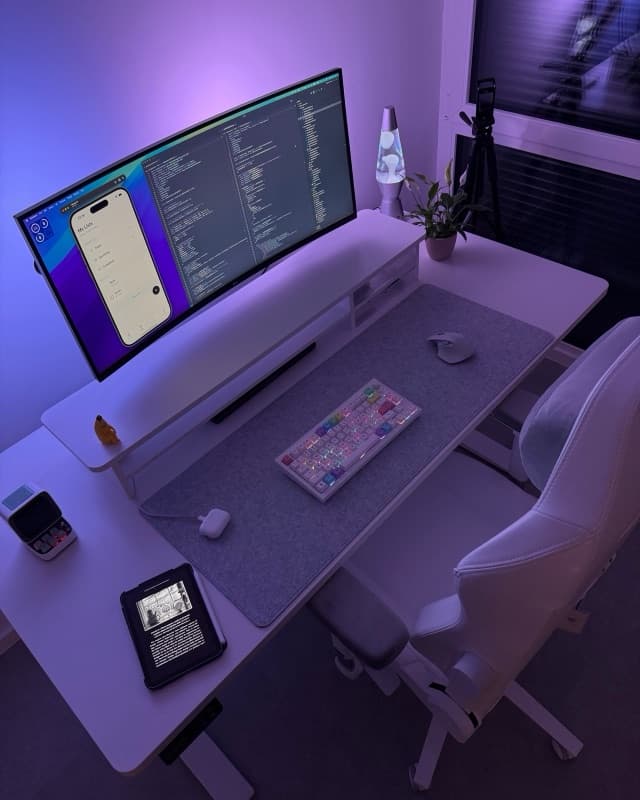 My desk at night: an ultrawide monitor full of code under purple light